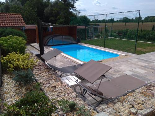 a swimming pool with two lawn chairs and a swimming pool at Apartmán u potoka in Sadov