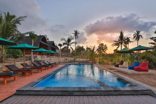 una piscina con sedie e ombrelloni in un resort di Mamaras Guest House a Nusa Penida