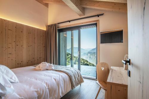 um quarto com uma cama e uma grande janela em Montanara Chalet em Fai della Paganella