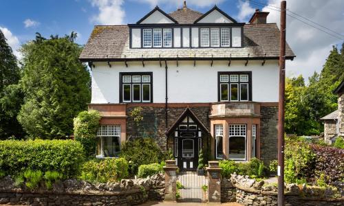 an old house with a stone fence in front of it at The Firs in Bowness-on-Windermere