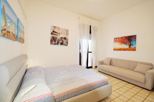 a white bedroom with a bed and a couch at Magica Immobiliare - Bagni Miramare 21 in Lido di Jesolo