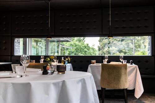 a dining room with white tables and chairs and windows at Hotel Sanglier in Durbuy