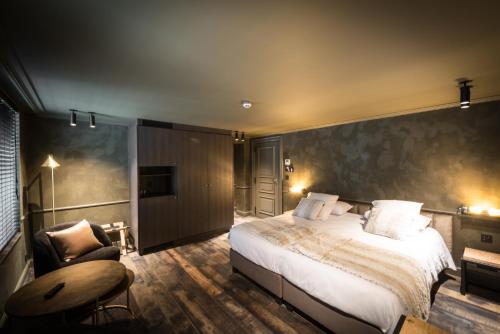 a bedroom with a large bed and a chair at Hotel Sanglier in Durbuy