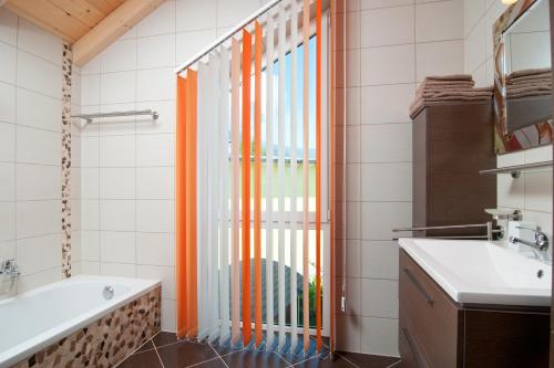 an orange curtain in a bathroom with a tub and a sink at Seevilla & Seehaus Erna in Faak am See