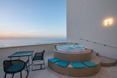a hot tub on a balcony with a table and chairs at Hotel Grotta Palazzese in Polignano a Mare
