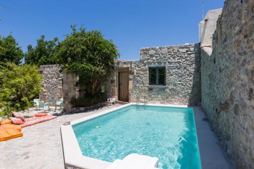 a swimming pool in front of a stone house at Muazzo Creta Stone House, Nature Escape with Pool, By ThinkVilla in Pigi