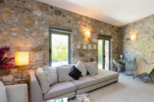 a living room with a couch and a stone wall at Muazzo Creta Stone House, Nature Escape with Pool, By ThinkVilla in Pigi