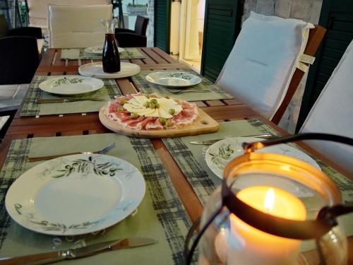 a table with plates and a candle and a pizza at VILLA MATIJA in Cesarica