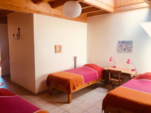 une chambre avec deux lits et une table dans l'établissement Le Champ, à La Chaise-Dieu