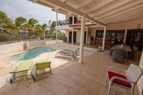 a patio with a pool and chairs and a table at Casa Coco Bonaire at Sabalpalm Villas in Kralendijk