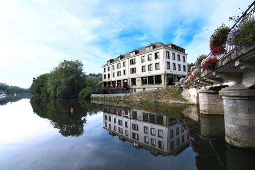 a building on a bridge next to a river at Hôtel Restaurant Du Château in Josselin