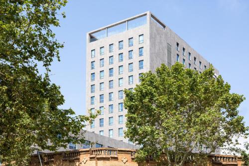 a tall white building with trees in front of it at Acta Voraport in Barcelona