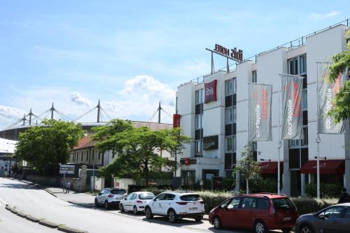 una strada con auto parcheggiate di fronte a un edificio di ibis Saint-Denis Stade Ouest a Saint-Denis