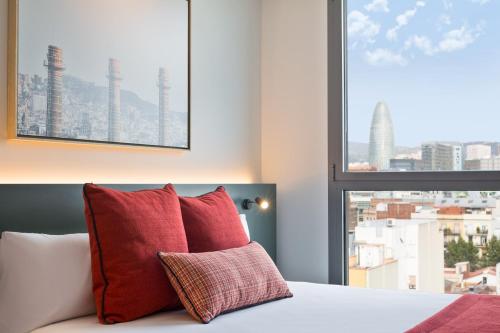 a bedroom with a bed with red pillows and a window at Acta Voraport in Barcelona