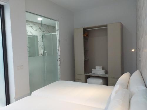 a white bedroom with a shower and a bed at Apartamentos Rivero 8 in Seville
