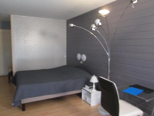 a bedroom with a bed and a lamp and a chair at Hotel Les Gravades Ussel in Ussel