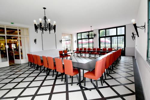a dining room with a long table and orange chairs at Hôtel Restaurant Du Château in Josselin