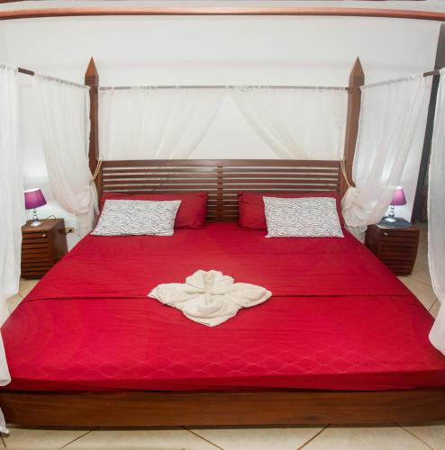 a bedroom with a red bed with a red blanket at Punta Duarte Garden Inn in Los Duarte