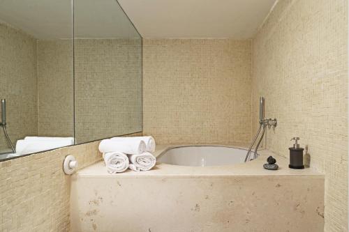 a bathroom with a tub with towels and a mirror at Design in Genoa City Center by Wonderful Italy in Genova