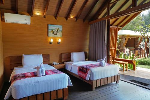 2 letti in una camera con pareti in legno e pavimenti in parquet di Wah Resort Gili Trawangan a Gili Trawangan