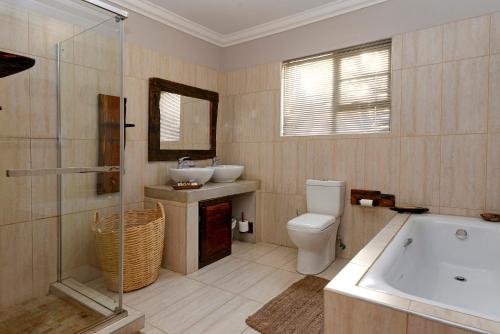 a bathroom with a tub and a toilet and a sink at Sweni Lodge 91 Mjejane Kruger Park in Hectorspruit