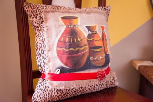 a pillow with three vases on it on a table at Calabash Apartment-Hotel in Kotu