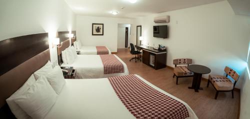 a hotel room with two beds and a desk at Costa del Sol Wyndham Chiclayo in Chiclayo