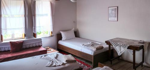 a room with two beds and a table and windows at Lori's traditional house in Gjirokastër