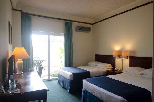 um quarto de hotel com duas camas e uma porta de vidro deslizante em Hotel Berlin em San Salvador