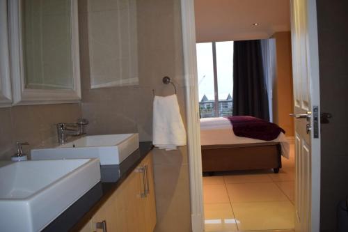 a bathroom with a sink and a bed with a window at Two bedroom apartment at the Sails in Durban