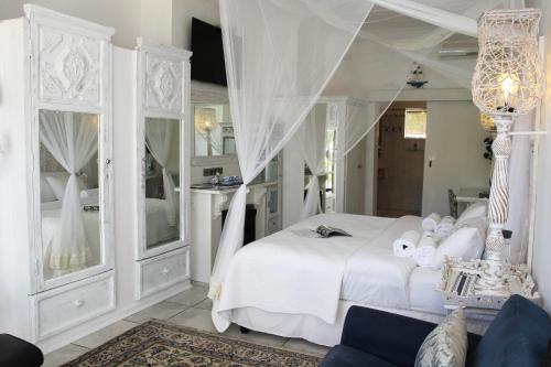 Un dormitorio con una cama blanca y una lámpara de araña. en Belurana River Manor, en Upington