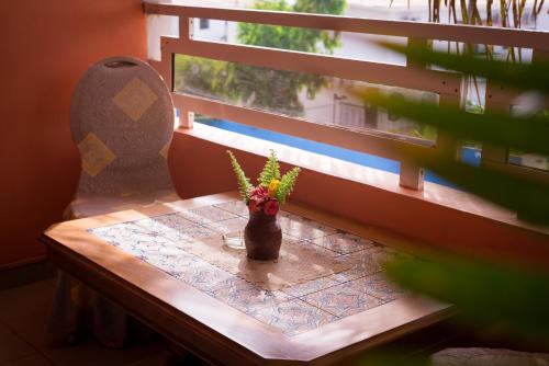 a table with a vase with a plant on it next to a window at Calabash Apartment-Hotel in Kotu