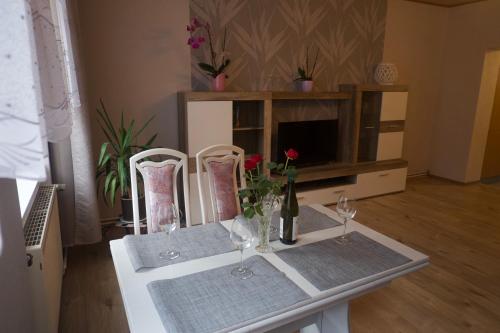 una mesa con dos copas de vino y flores en ella en Ferienwohnung Kroppenmühle, en Schönburg
