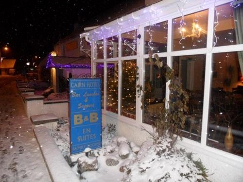 een bord in de sneeuw voor een gebouw bij Cairn Hotel in Carrbridge