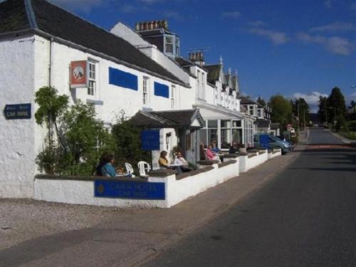 un gruppo di persone seduti fuori da un edificio di Cairn Hotel a Carrbridge