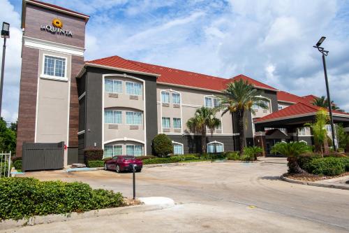 a hotel with a car parked in a parking lot at La Quinta by Wyndham Houston East at Normandy in Houston