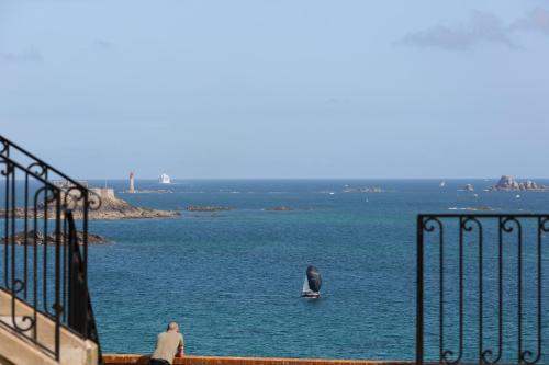 a man standing next to a body of water with a sailboat at L'Entre Deux Mers - Belle maison 8 personnes in Dinard
