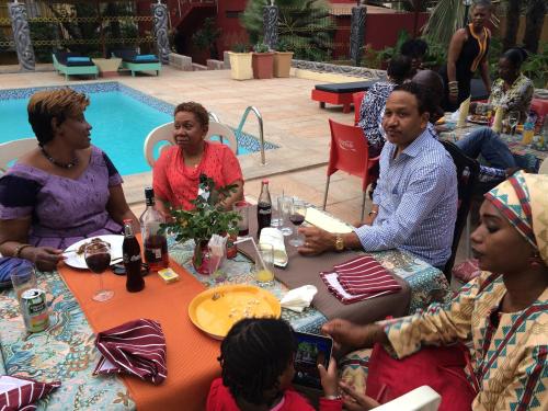 a group of people sitting around a table by a pool at Calabash Apartment-Hotel in Kotu