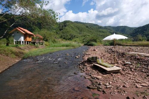 a table with an umbrella next to a river at ต้นน้ำน่าน บ่อเกลือ in Ban Sale