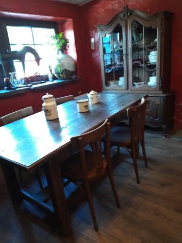 a wooden table and chairs in a room with red walls at B&B Chambre d'hôtes de la Vecquée in Stoumont