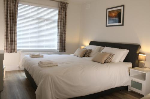 een groot wit bed in een slaapkamer met een raam bij The Iris in Criccieth