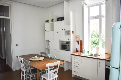 a kitchen with white cabinets and a wooden table at A Casa da Cascata in Ribeira Grande