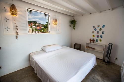 a bedroom with a white bed and a window at Casa Love in Sayulita
