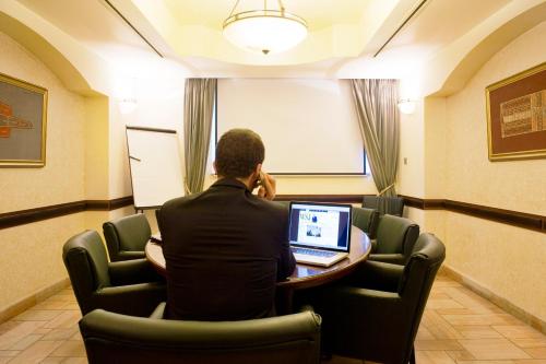 a man sitting at a table with a laptop at The American Colony Hotel - Small Luxury Hotels of the World in Jerusalem