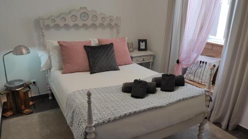 a bedroom with a white bed with pink pillows at Casa 40th-Music Wood House in Óbidos