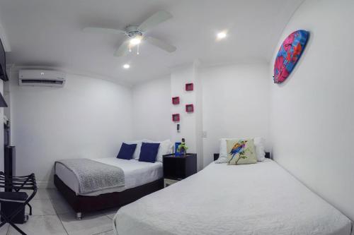 a bedroom with two beds and a clock on the wall at Hotel Las Lunas in San Andrés