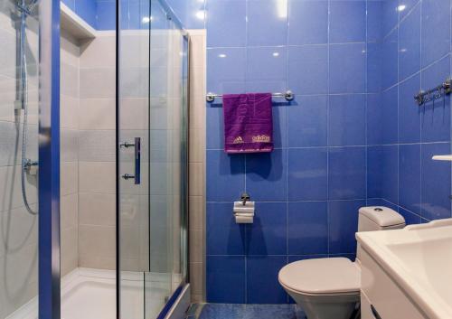 a blue tiled bathroom with a toilet and a shower at Apartment Amaghleba in Tbilisi City