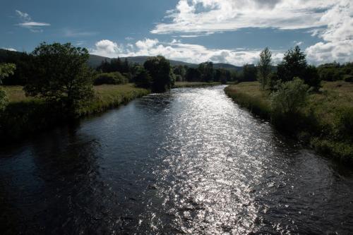 a riverurrency with a bridge in a field at Macdonald Cardrona Hotel, Golf & Spa in Peebles