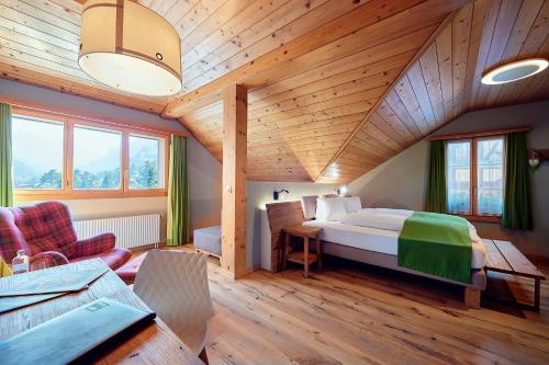 - une chambre avec un grand lit dans une pièce dotée de plafonds en bois dans l'établissement Hotel National, à Frutigen