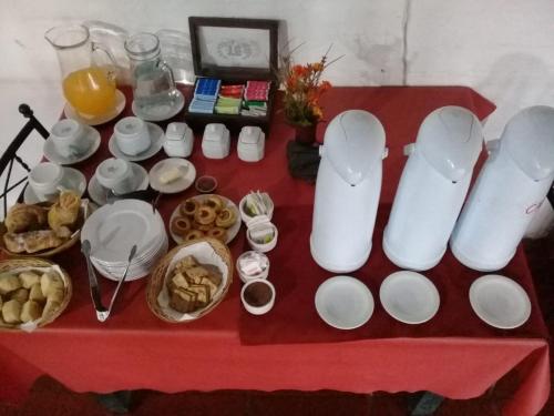Hostería Niemanu في باسو دي لا باتريا: طاولة حمراء مليئة بالأطباق البيضاء والأكواب والطعام